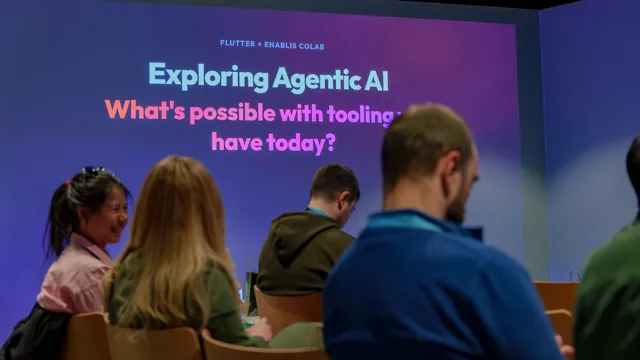 The opening slide reading "Exploring Agentic AI: what's possible with the tooling we have today?" projected behind the seated audience in Flutter's immersive zone